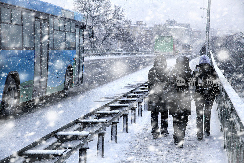 人们在下雪的冬天在城市街道上