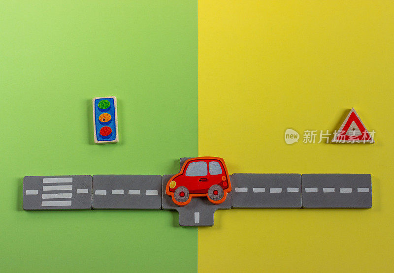 小木制玩具车，路标和道路。黄绿色背景上的微型儿童汽车模型。文本复制空间