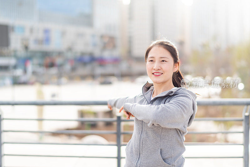 亚洲年轻女子站和伸展后，在城市跑步