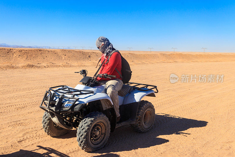 年轻人在埃及沙漠狩猎旅行驾驶ATV。在埃及赫尔加达附近的沙漠里骑四轮摩托车旅行