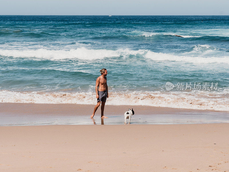 一个年轻人在海滩上和狗玩耍