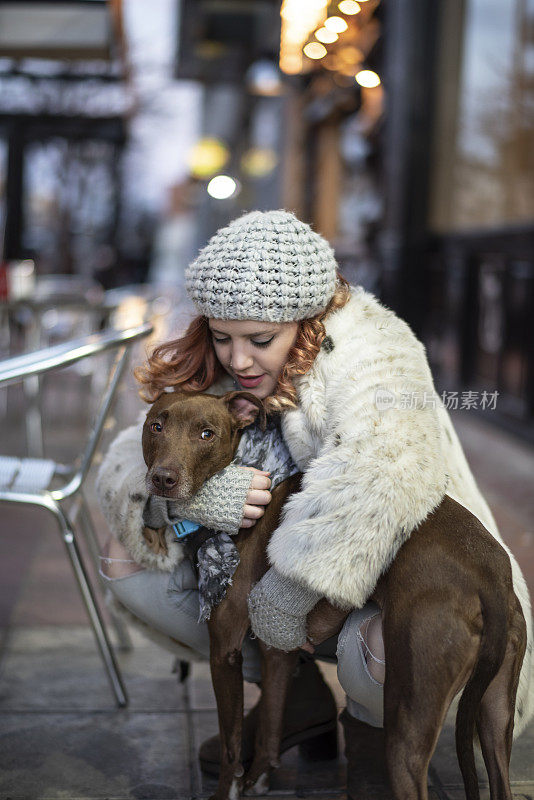 冬夜里，蜷着身子的女人会拥抱她的狗，保护它免受寒冷。晚上大街上背景