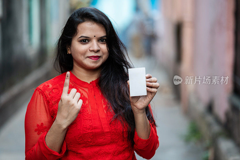 一名年轻女子在选举中投完票后，展示她沾有墨水的手指和选民身份证。