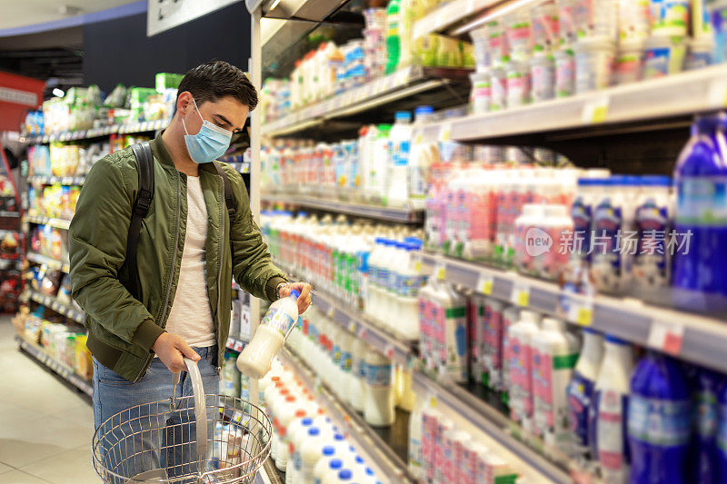 健康、安全和大流行概念-年轻男子戴防护医用口罩，以防止在超市背景下感染病毒