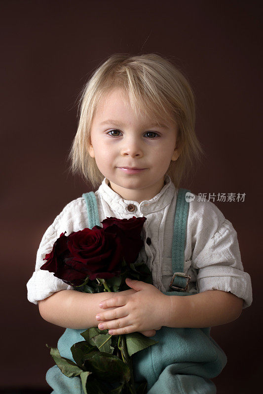 漂亮的小男孩，拿着红玫瑰庆祝母亲节