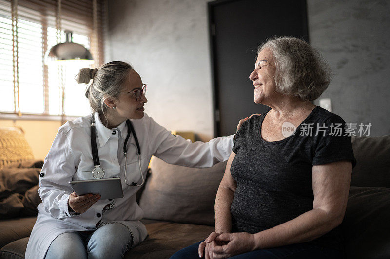 医生在家访中使用数字平板电脑安慰老年妇女