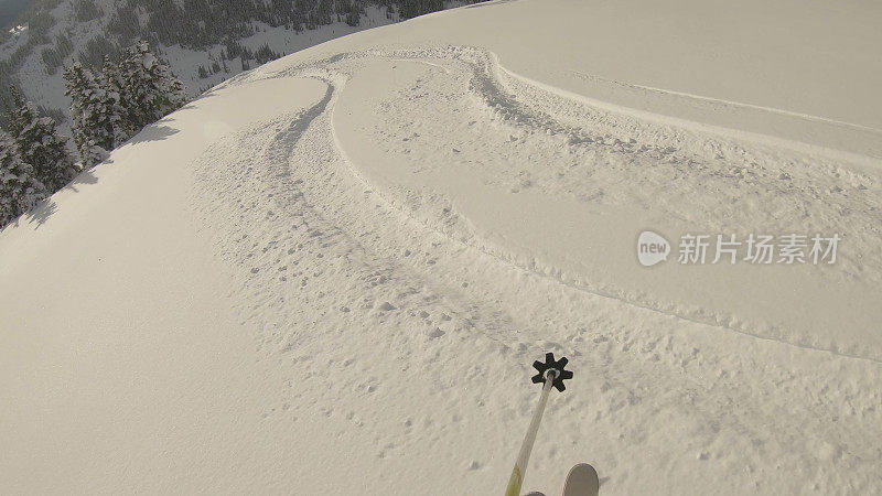 当滑雪者通过厚厚的粉状雪下坡时