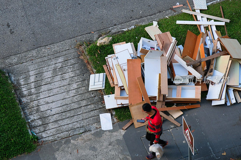 一堆从组屋装修中拆除的家具、厨柜货架被不负责任的装修承包商丢弃在人行道上;碎片和建筑废料。