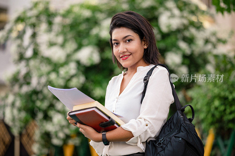 年轻的女学生拿着书，检查她的笔记