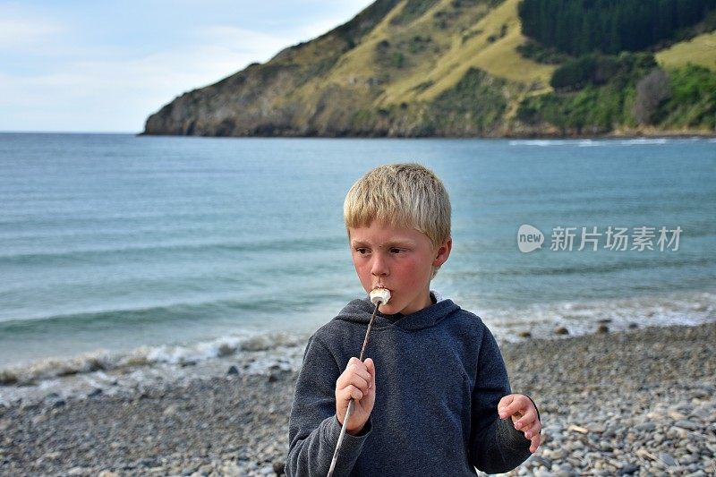 男孩在海边吃煮棉花糖