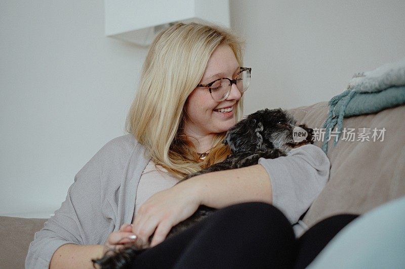 一个女人在沙发上抱着一只狗
