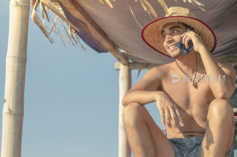 在拉丁美洲厄瓜多尔瓜亚斯省的普拉亚斯，一位拉丁健康男子一边打电话一边冲浪