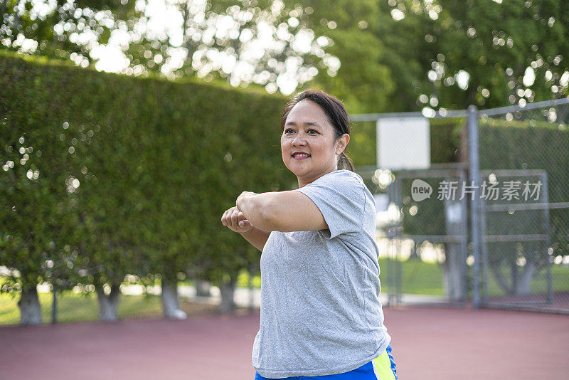 成熟的菲律宾女人打网球前伸展