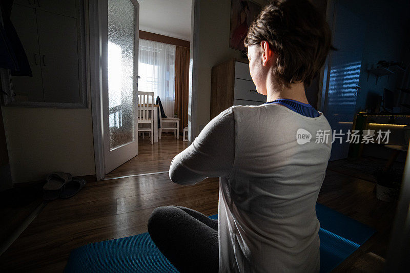 一个女人在她的公寓里练瑜伽。日落时分公寓的灯光效果。