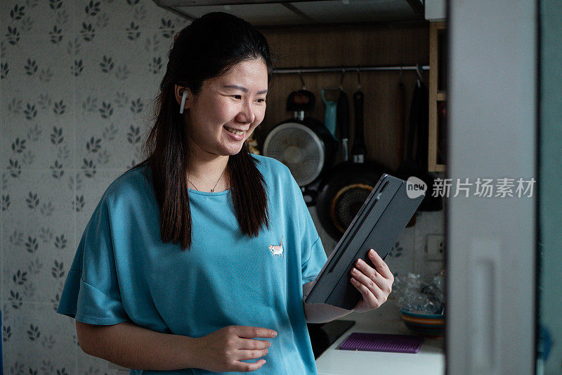 在家工作:一名年轻女性用电子平板电脑阅读或观看东西