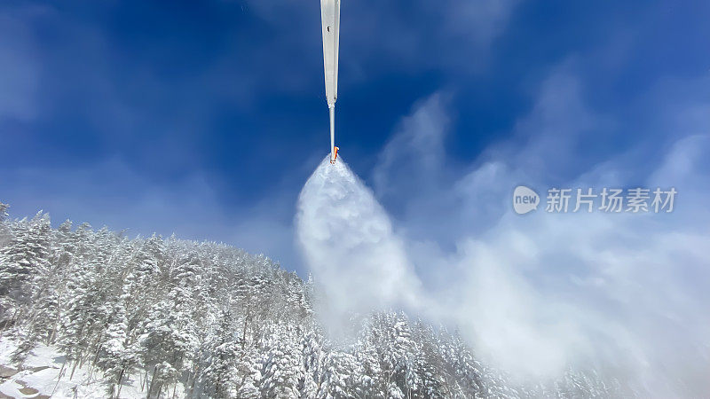 雪炮在滑雪坡和树木上喷洒人工雪