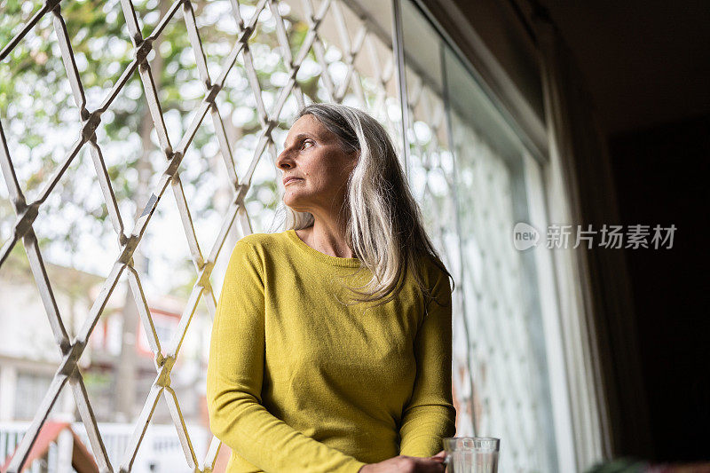 一个成熟的女人从家里的窗户往外看