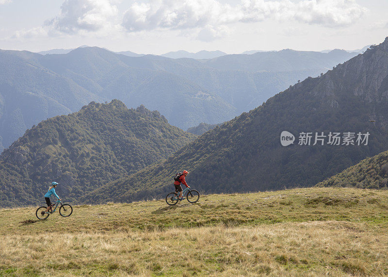 山地自行车手沿着长满草的山脊行进