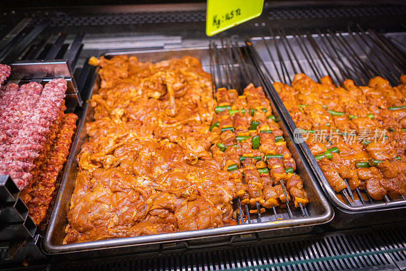 新鲜的生牛排和烤肉串品种在屠夫柜台。