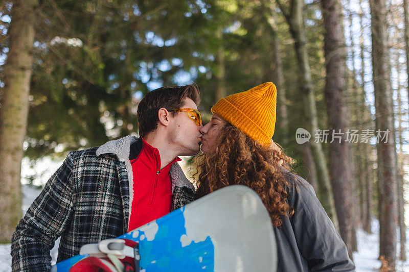 美丽的年轻夫妇在森林中接吻，而滑雪冬季旅行