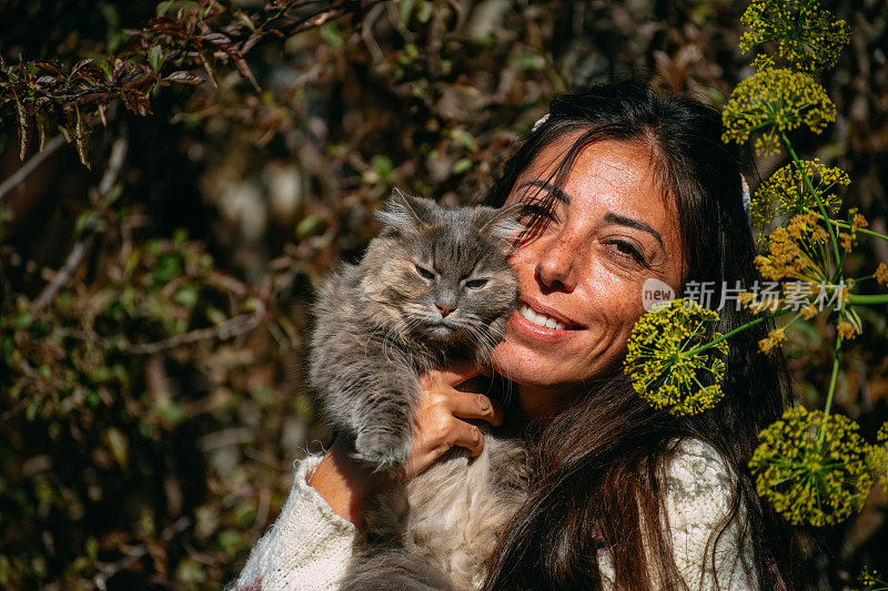 年轻女子在花园里抱着她的猫