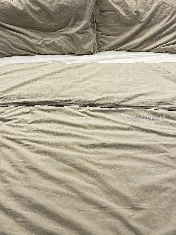 米色全框形象，双人床羽绒被和枕头在国内卧室，皱褶羽绒被盖，室内卧室设计