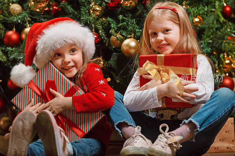 在圣诞树旁，女朋友的女孩们开心地拥抱着送给彼此的珍贵的圣诞礼物