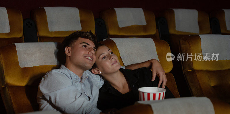年轻夫妇在电影院看电影，很幸福