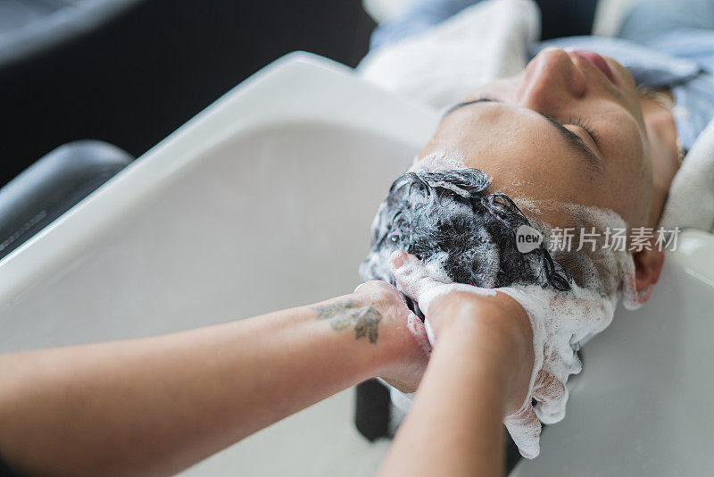 一位拉丁女性专业发型师正在为她的客户洗头