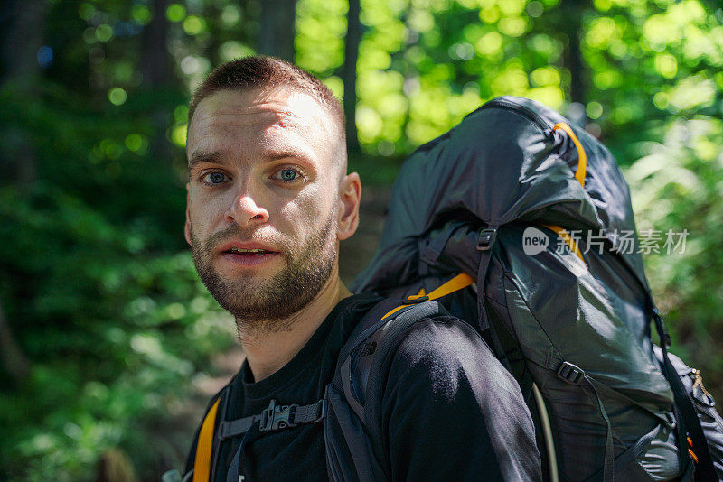 徒步旅行者的肖像与旅游背包在树林里