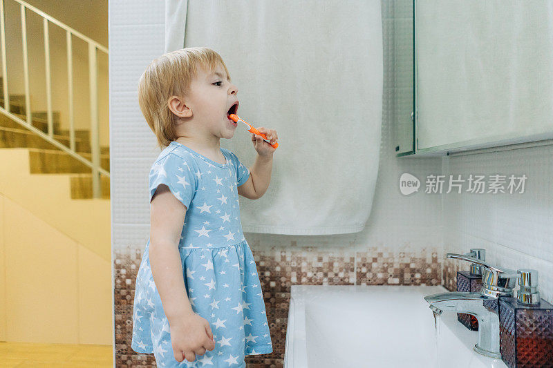 一个小女孩在浴室里学着自己刷牙。