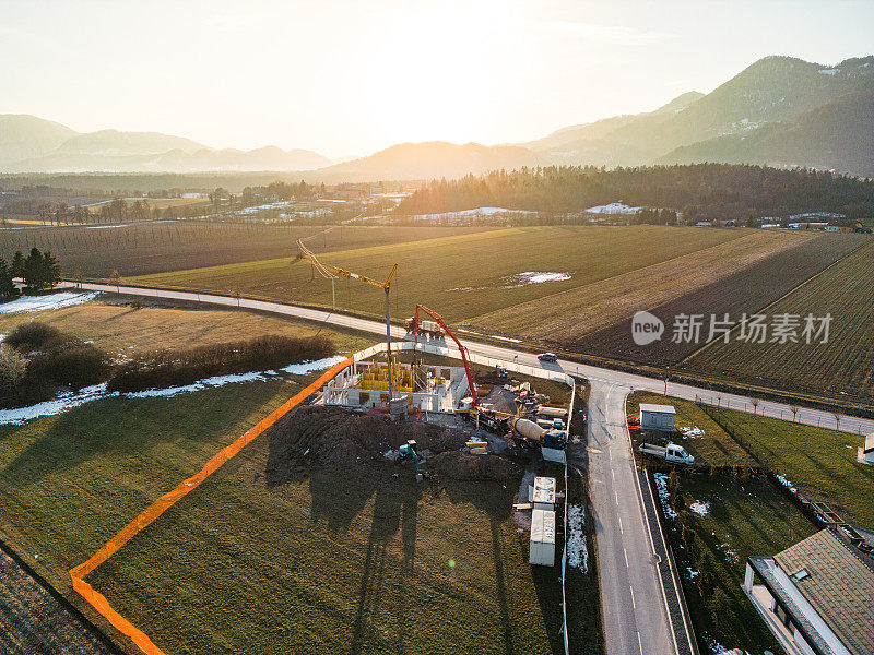 鸟瞰混凝土泵搅拌车在新建筑工地浇筑混凝土，日落视图