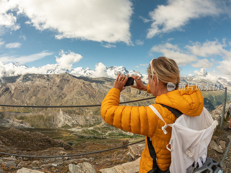 一位在山顶上用手机拍照的运动女子