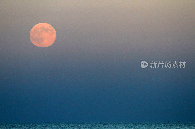 红月亮升起在蓝色的海面上
