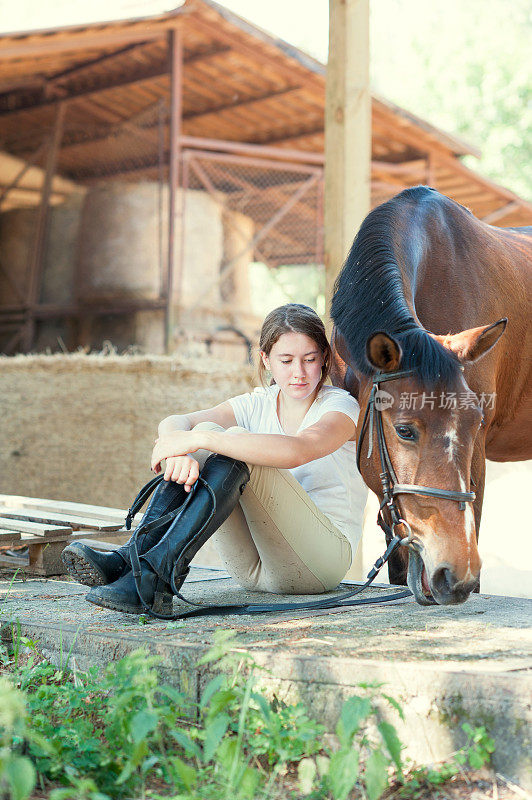 年轻的少女骑马坐在她最喜欢的马旁边