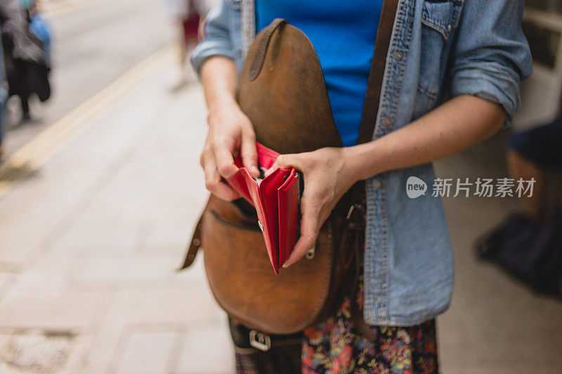 年轻女子拿着钱包走在街上