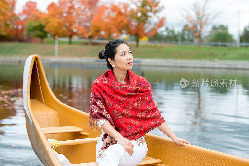 亚洲女性在独木舟在秋天的色彩观光旅行