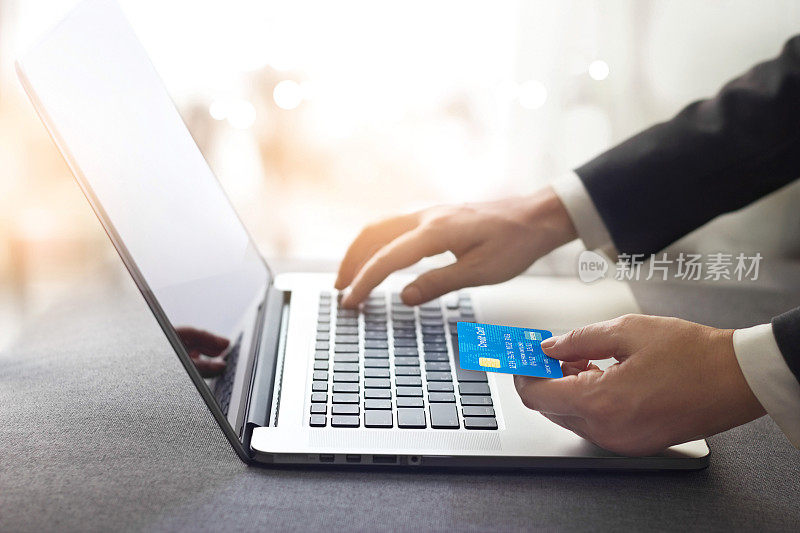 手握信用卡和使用笔记本电脑的商人，网上购物的概念