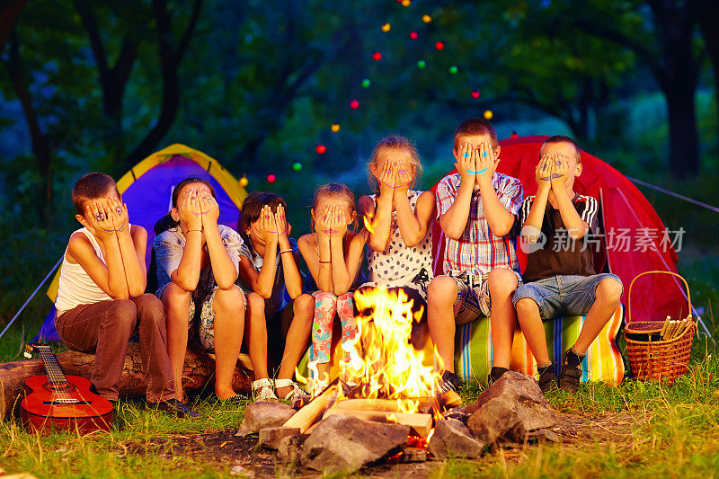 手上画着脸的孩子们围坐在篝火旁