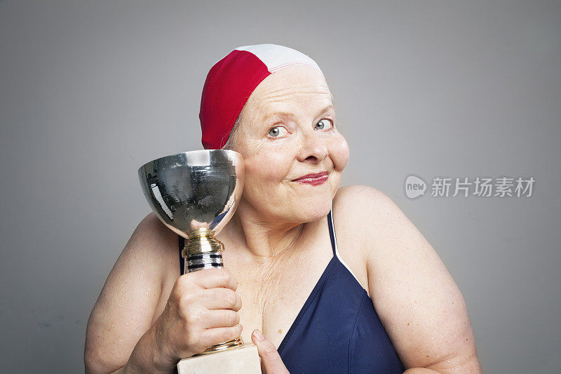 成熟的女性获胜者与奖杯穿泳装
