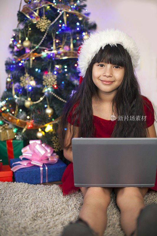一个亚洲小女孩在用圣诞节收到的新笔记本电脑