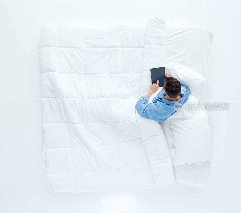 上图为人躺在床上使用平板电脑