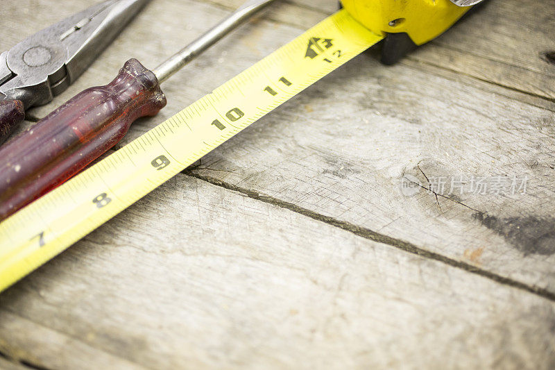木桌上的施工工具。钳子，螺丝刀，卷尺。