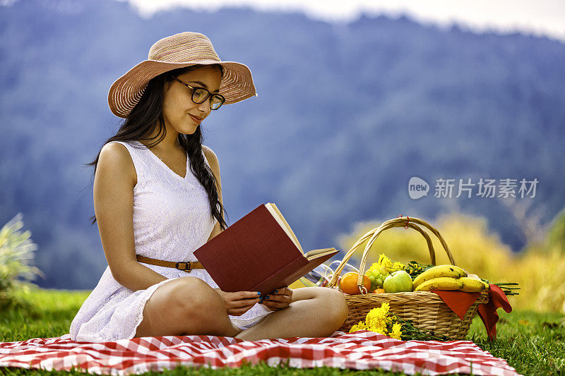 放松的年轻女子坐在草地上看书