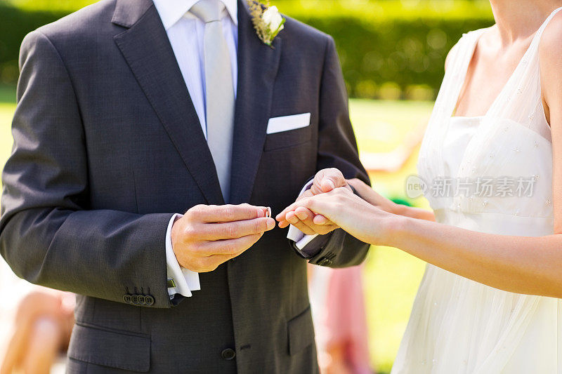 在花园婚礼上，新郎给新娘戴上戒指