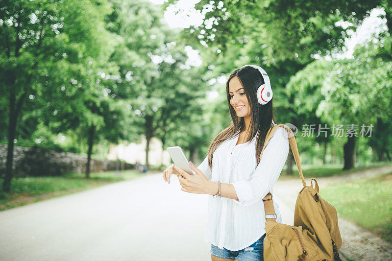 女学生戴着耳机在公园里听音乐