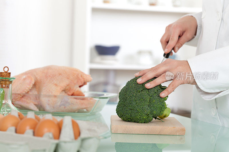 厨师切花椰菜，准备生鸡肉