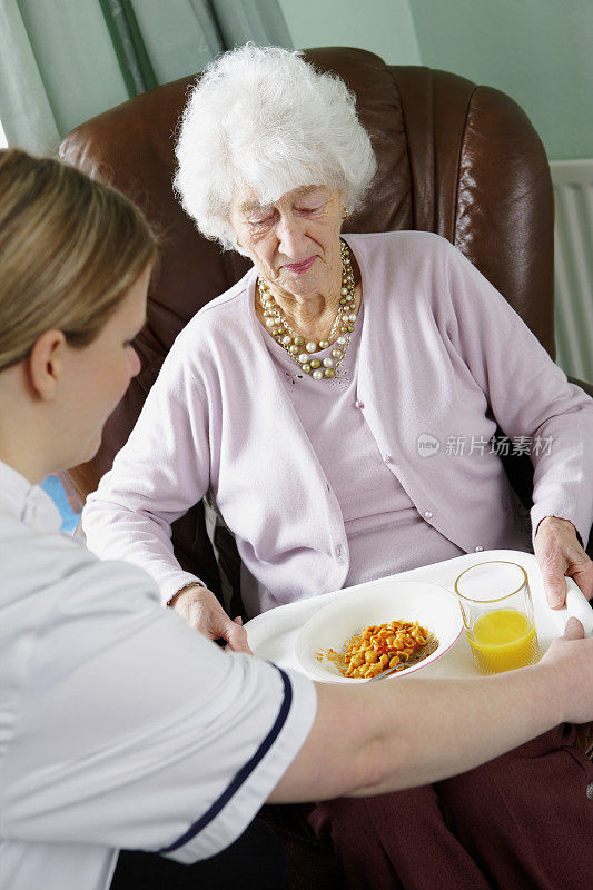 年轻的护士在敬老院给老太太送饭