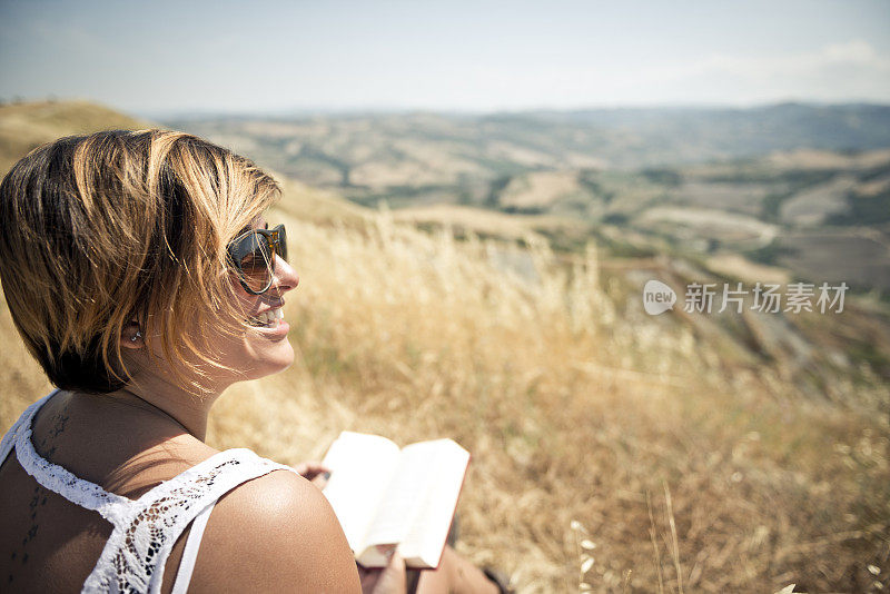 年轻女子微笑着读着一本书