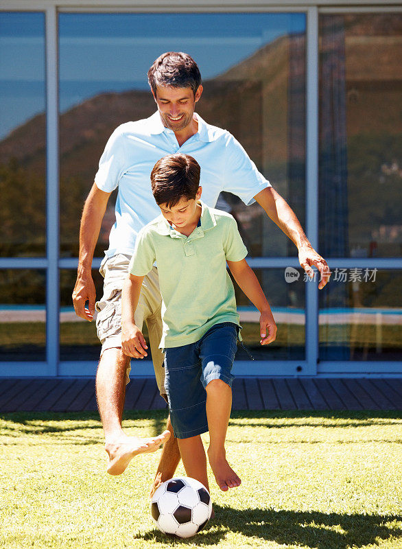 小男孩和他的爸爸在踢足球